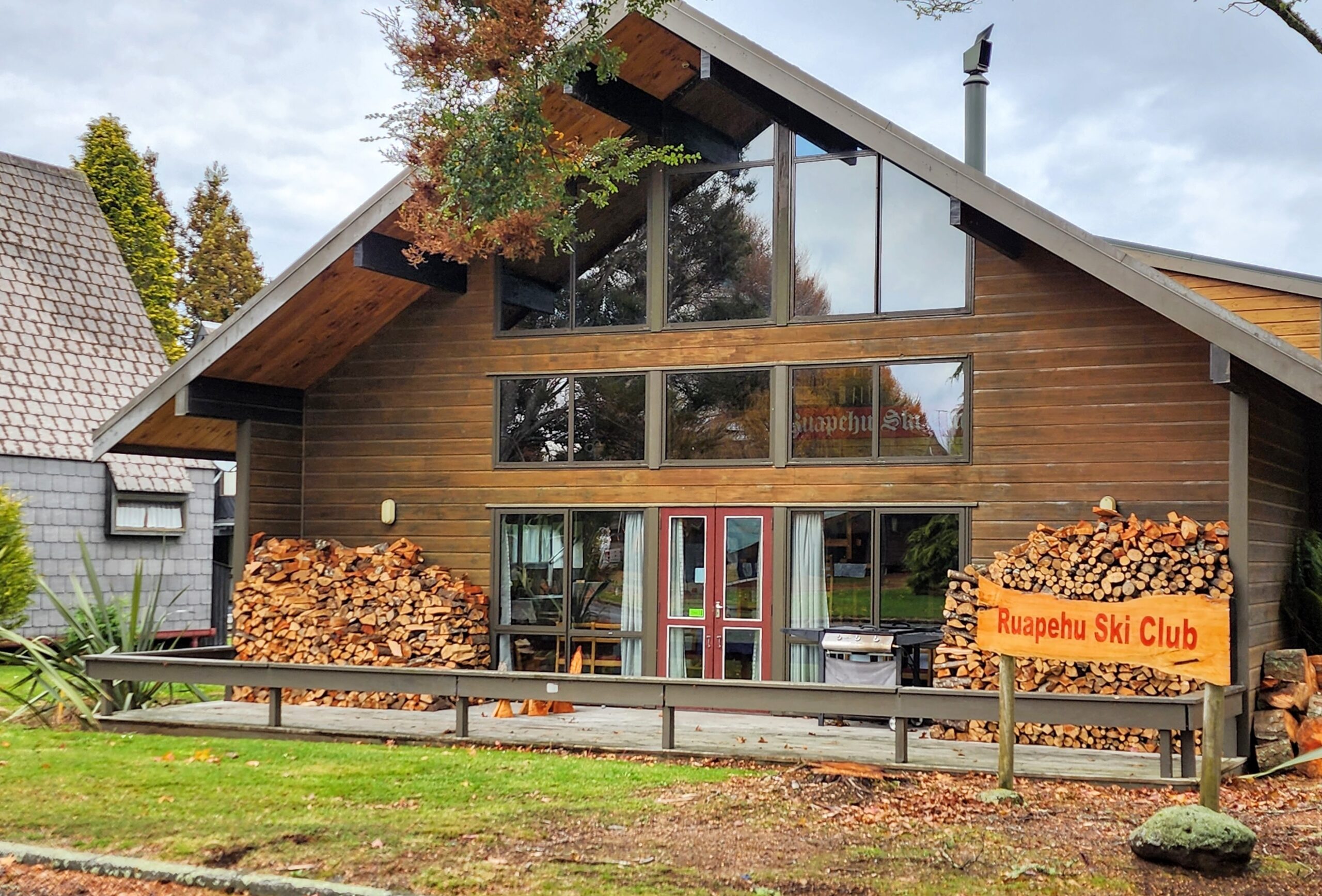 Turoa Lodge, a two-storey timber and glass building among trees at Ohakune